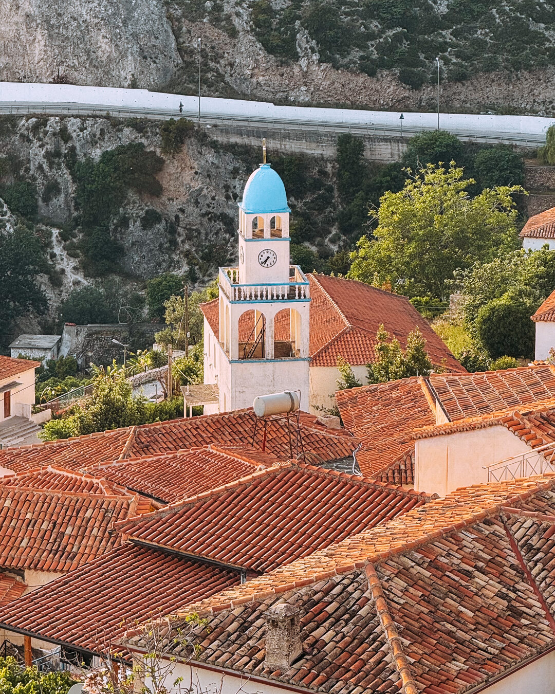 point de vue sur l'église blanche et bleu du village de dhermi en albanie