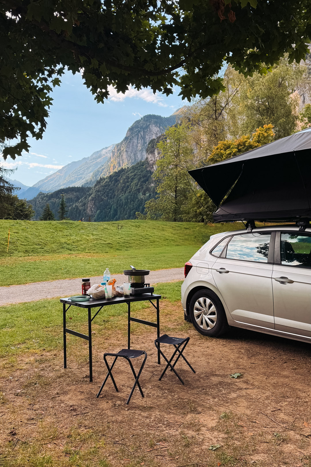 Voiture équipée d’une tente de toit TentBox, avec un coin cuisine installé au camping face aux montagnes de Lauterbrunnen, en Suisse.