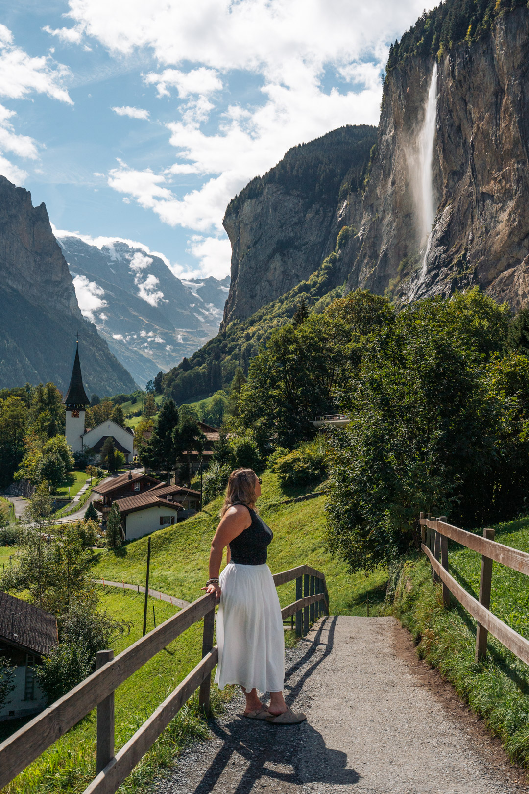 Mélanie sur un sentier à Lauterbrunnen, avec la cascade de Staubbach, l’église du village et les montagnes suisses en arrière-plan
