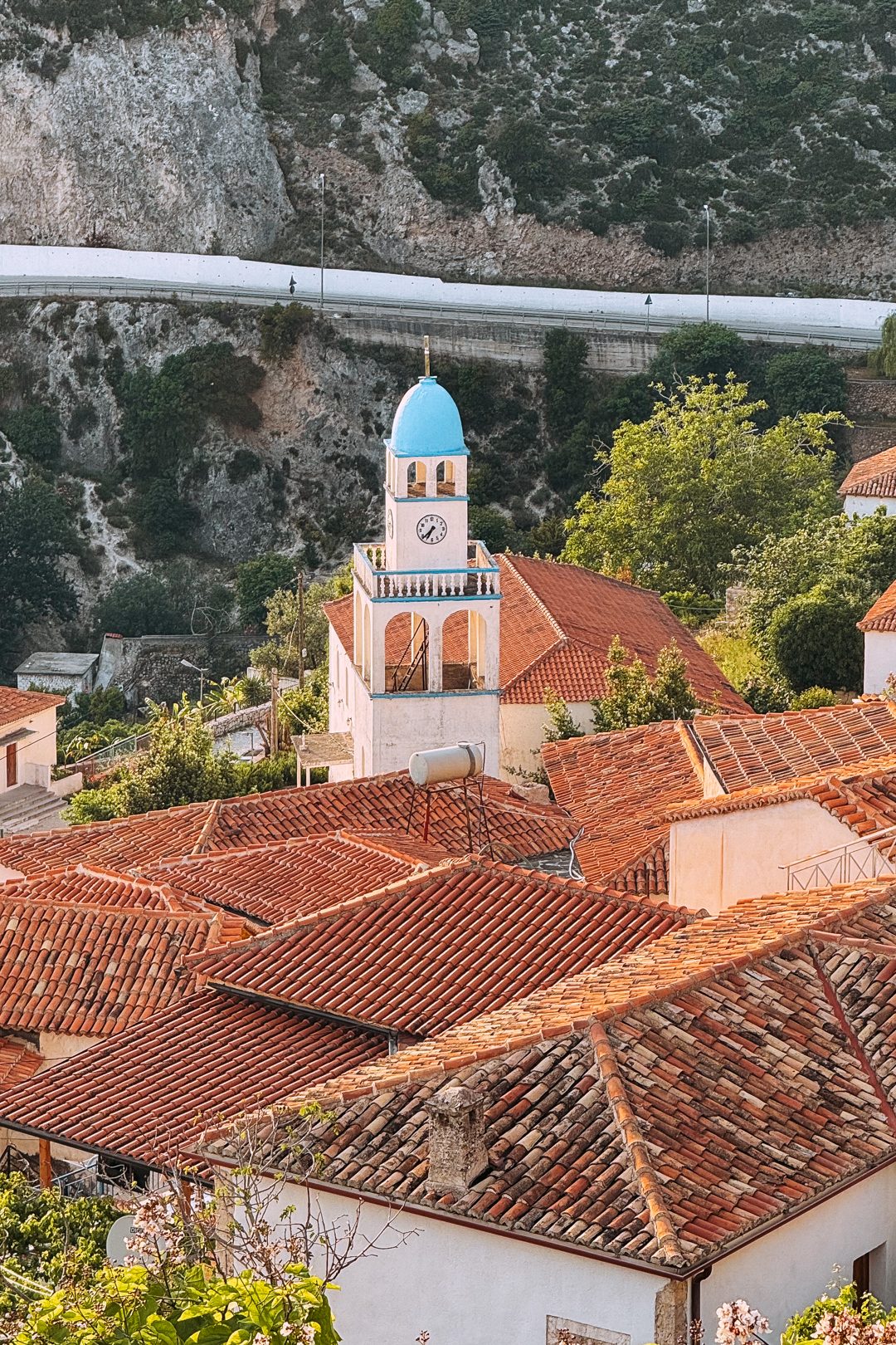 point de vue sur l'église blanche et bleu du village de dhermi en albanie